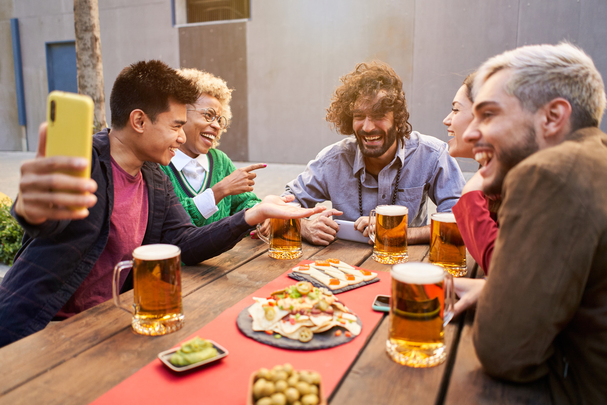 friends taking selfie and drinking beer at bar