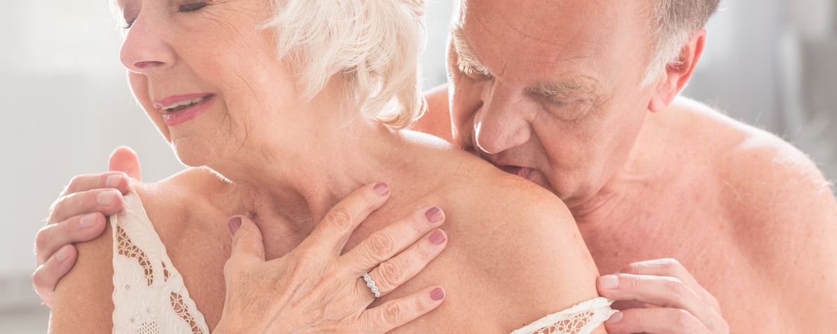 older man kissing wife in lingerie