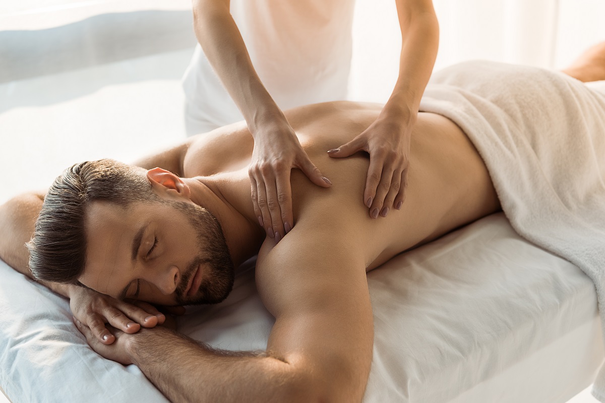 cropped view of woman doing massage to man with closed eyes